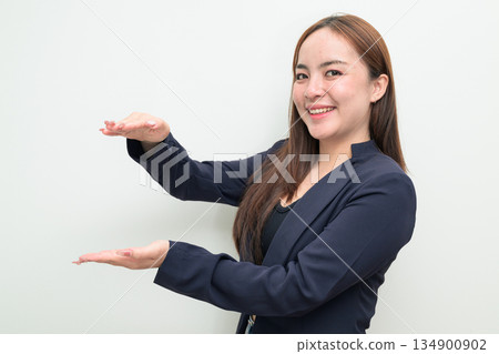 Portrait of a young Asian businesswoman against white background measuring amount with hands Portrait of a young Asian businesswoman against white background measuring amount with hands 134900902
