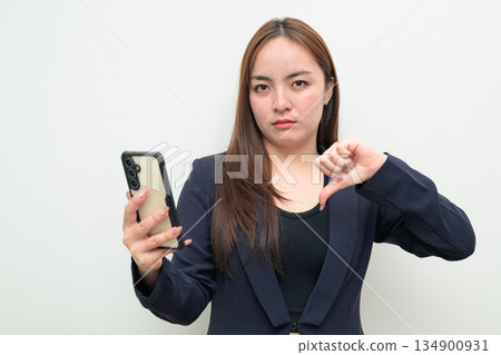 Portrait of a young Asian businesswoman against white background using phone Portrait of a young Asian businesswoman against white background using phone 134900931