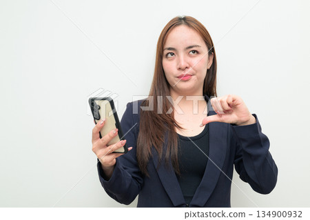 Portrait of a young Asian businesswoman against white background using phone 134900932
