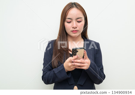 Portrait of a young Asian businesswoman against white background using phone 134900934