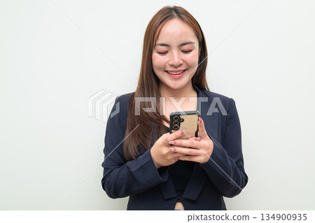 Portrait of a young happy Asian businesswoman against white background using phone smiling 134900935