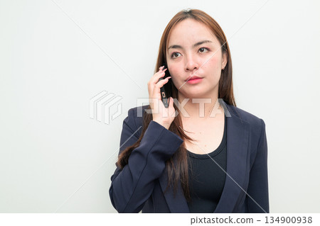 Portrait of a young confident Asian businesswoman against white background on the phone talking 134900938