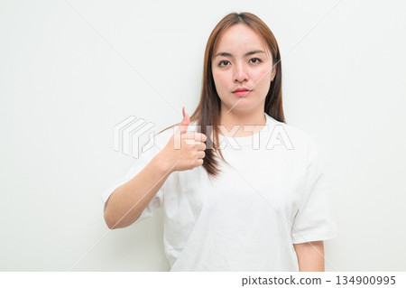 Portrait of a young Asian woman against white background giving thumbs up 134900995