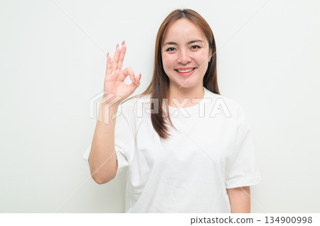 Happy young Asian woman against white background wearing t-shirt and smiling Happy young Asian woman against white background wearing t-shirt and smiling 134900998
