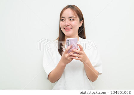 Portrait of a young happy Asian woman against white background using mobile phone Portrait of a young happy Asian woman against white background using mobile phone 134901008