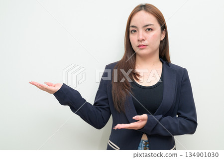 Portrait of a young Asian businesswoman against white background showing open palm hand gesture Portrait of a young Asian businesswoman against white background showing open palm hand gesture 134901030