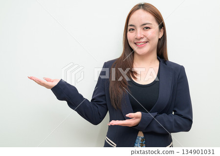 Portrait of a young Asian businesswoman against white background showing open palm hand gesture 134901031