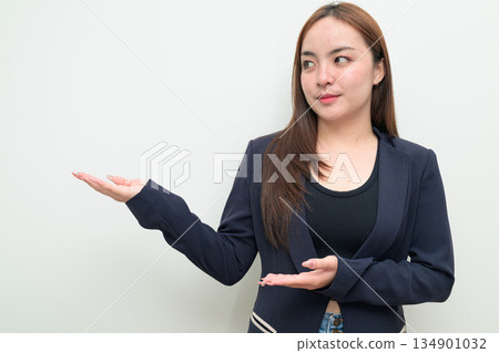 Portrait of a young Asian businesswoman against white background showing open palm hand gesture 134901032