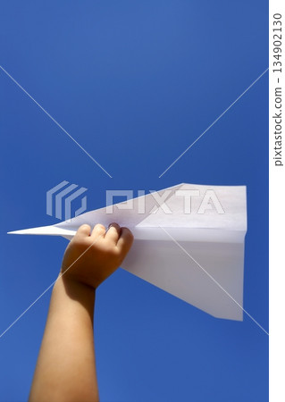 Paper airplane in children hand over blue sky 134902130