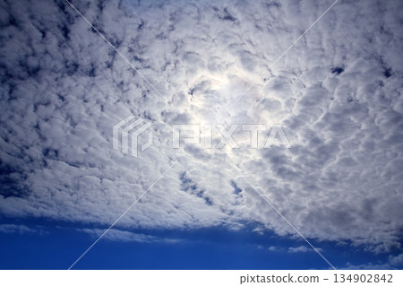 cirrocumulus clouds with sun glowing in blue sky 134902842