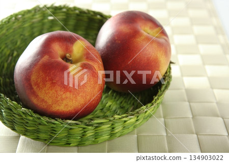 Two red peaches in a green basket Two red peaches in a green basket 134903022
