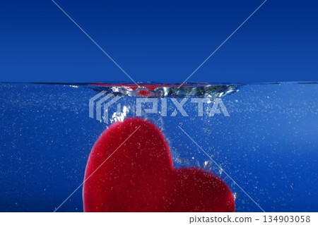 Candy red heart shape sinking into the blue water 134903058