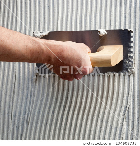 construction notched trowel with white cement 134903735