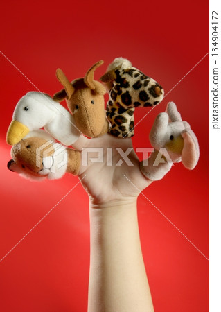 Finger puppets on a toddler hand over red Finger puppets on a toddler hand over red 134904172