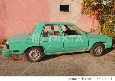 aged old vintage green car in pink wall aged old vintage green car in pink wall 134904221