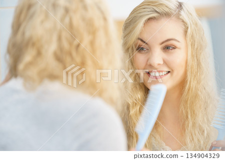 Woman getting ready in bathroom, combing hair. Woman getting ready in bathroom, combing hair. 134904329
