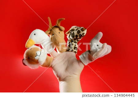Finger puppets on a toddler hand over red Finger puppets on a toddler hand over red 134904445