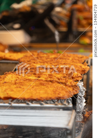 Traditional Hungarian langos frying at street food stall during outdoor market in Budapest, showing golden crispy dough and hot oil atmosphere 134904719