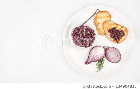 Caramelized red onion jam served with toasted bread slices on white plate with copy space, top view 134904835