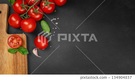 Fresh ripe cherry tomatoes with basil, garlic and salt on black background with copy space for food design and cooking concept 134904837