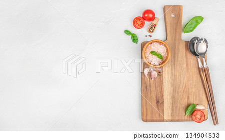Minimal kitchen flat lay with wooden cutting board, tomatoes, basil, salt and utensils on white background with copy space Minimal kitchen flat lay with wooden cutting board, tomatoes, basil, salt and utensils on white background with copy space 134904838
