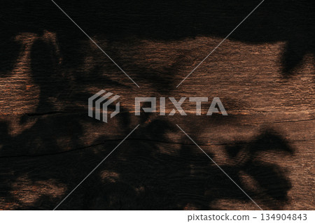 Dark rustic wooden background with dramatic leaf shadows and natural texture 134904843