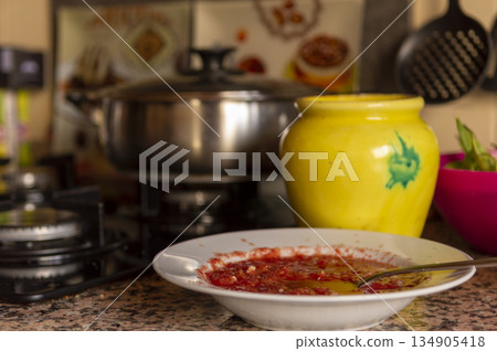 white dish with tomato and crushed garlic with kitchen utensils in the background white dish with tomato and crushed garlic with kitchen utensils in the background 134905418