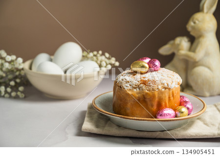 Spring holiday background. Easter Cake with chocolate colorful eggs, gypsophila flowers and cute bunnies Spring holiday background. Easter Cake with chocolate colorful eggs, gypsophila flowers and cute bunnies 134905451