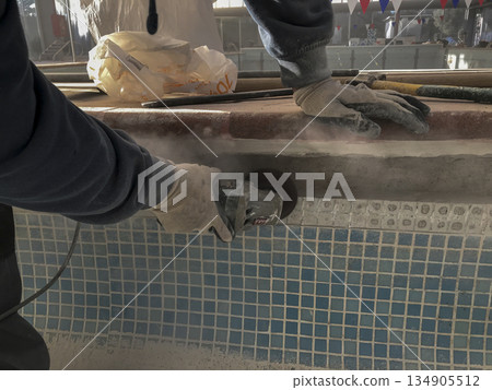 person working in a swimming pool with a small radial saw 134905512