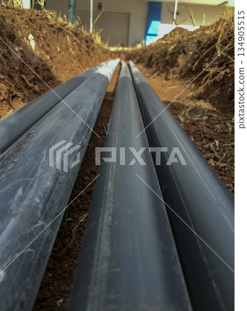 pvc pipes laid in parallel inside a trench in the ground 134905515