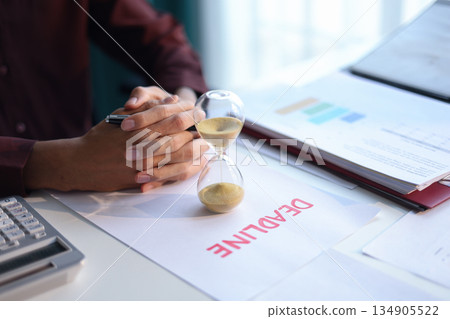 Businessman working on office desk with deadline document and running sand clock. Time management concept. 134905522