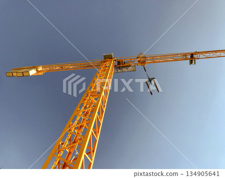 metal construction site jib crane with pallet carrier and blue sky in the background metal construction site jib crane with pallet carrier and blue sky in the background 134905641