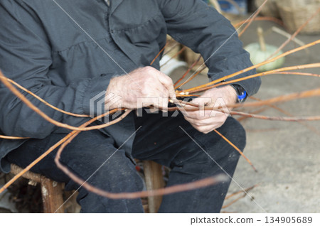 close-up of a wicker craftsman's hands preparing a basket 134905689