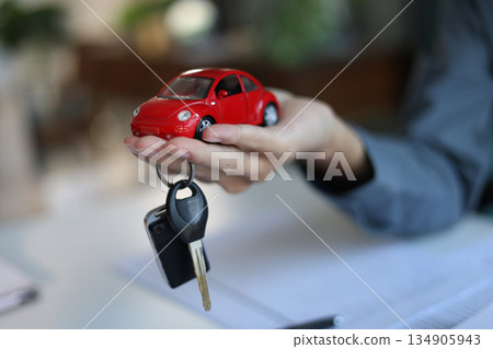 Car model and car key in hand. Concept for car loan, lease, insurance, buying or selling. 134905943