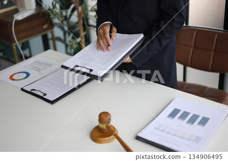 Legal counsel reading contract paperwork to finalize a legal agreement. Concepts for legal counsel, judicial authority, and the finality of a decision or agreement. 134906495