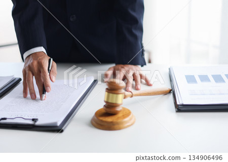 Legal counsel reading contract paperwork to finalize a legal agreement. Concepts for legal counsel, judicial authority, and the finality of a decision or agreement. Legal counsel reading contract paperwork to finalize a legal agreement. Concepts for legal counsel, judicial authority, and the finality of a decision or agreement. 134906496