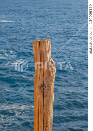 close up of thick wooden post with rough bark texture against deep blue ocean waves background close up of thick wooden post with rough bark texture against deep blue ocean waves background 134906529