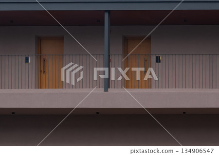minimalist modern hotel facade: two stories of identical wooden doors and balconies 134906547