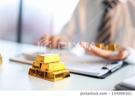 Gold bars on the table. Businessman invest in trading actual gold, calculating profit price of buy and sell gold. 134906561