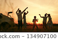 Happy family car trip, child parents picnic outdoor holiday, mother father kid dancing to music outdoors, people having fun, dancing across meadow, sunset dancing kids, bright orange sunset, weekend 134907100