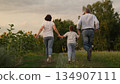 Family Walking in Nature, Grandparents with Grandchild Outdoors, Generations Together in Field, Peaceful Family Time, Holding Hands in Countryside, Spring or Summer Walk, Family Bonding Moments, Rural 134907111
