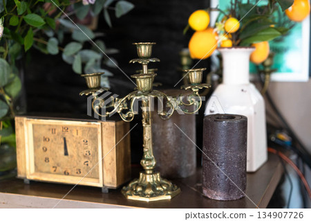 A beautifully arranged vintage display features an ornate candelabra, an antique clock, and floral accents. This charming setup invites family and friends to enjoy cozy dining moments together. A beautifully arranged vintage display features an ornate candelabra, an antique clock, and floral accents. This charming setup invites family and friends to enjoy cozy dining moments together. 134907726