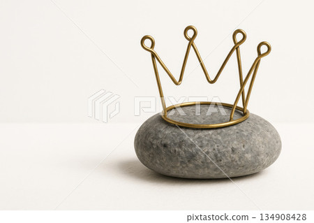 A golden crown made of wire on a gray stone. Space for text. A golden crown made of wire on a gray stone. Space for text. 134908428