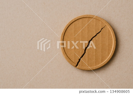 Cardboard coin with a crack on a neutral background. Space for text. Cardboard coin with a crack on a neutral background. Space for text. 134908605