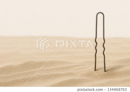 A hair clip stuck in the desert sand. Space for text. 134908703