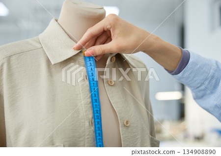 Woman clothing stylist measuring garment for precision in workshop 134908890