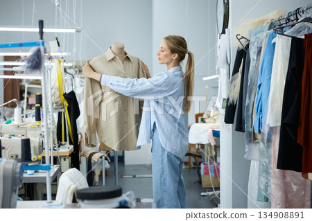 Craftswoman meticulously adjusts garment on mannequin within boutique sewing Craftswoman meticulously adjusts garment on mannequin within boutique sewing 134908891