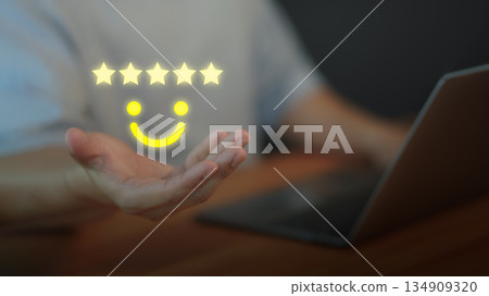 Customer satisfaction concept with five star rating and smile face above hand, symbolizing positive feedback, quality service, online reviews, testimonial, and excellent user experience. 134909320