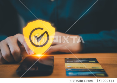 Online payment security concept with a hand touching a smartphone and a glowing shield checkmark, symbolizing safe digital transactions, data protection, and secure mobile banking and credit card use. 134909343