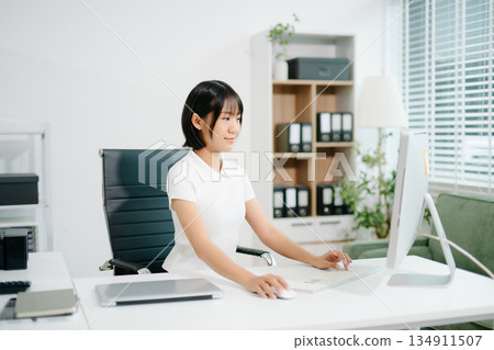 A focused office woman writing notes and working on paperwork at her desk, representing productivity, organization, business tasks, 134911507